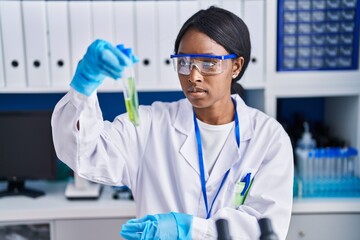 Young african american woman scientist holding test tubes at laboratory