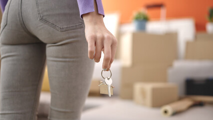 Young blonde woman holding key standing at new home