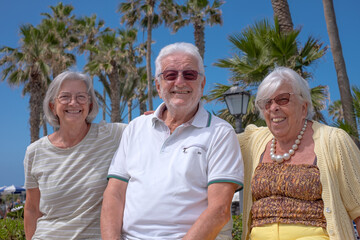Group of Happy Senior People Sitting Under the Sun close to the Beach Enjoying Sea Vacation and Freedom. Retirement Lifestyle Concept