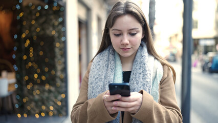 Young blonde woman using smartphone with relaxed expression at street