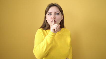 Young blonde woman standing with silent expression over isolated yellow background