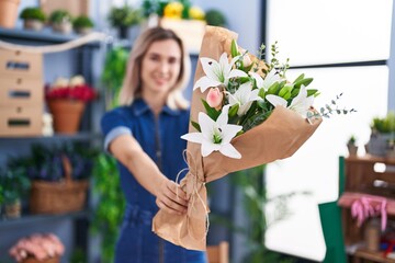 Young woman florist holding bouquet of flowers at florist
