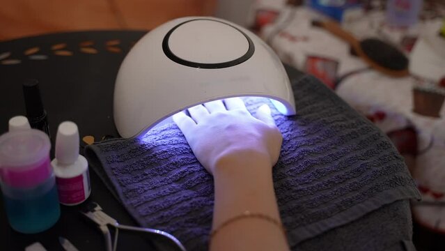 Using UV led lamp in beauty industry, woman drying applied nail gel polish under the shellac lamp, tools and instruments for doing manicure, beauty procedures and hygiene concept