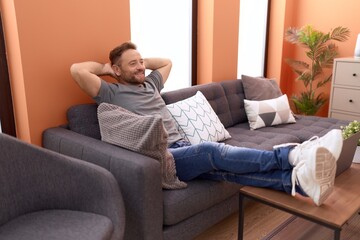 Obraz premium Middle age man relaxed with hands on head sitting on sofa at home