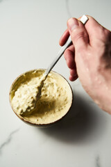 Classic Tartar Sauce dip in the bowl. The hand holds the spoon with the sauce. Mayonnaise with dill and capers plus lemon, shallot onion. Worcester sauce and Dijon Mustard. 