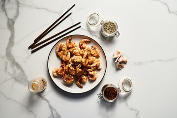 Crispy Pan fried tiger shrimps or prawns with garlic. Chinese or Asian cuisine dish. Shrimps lay on white plate on white marble background. Top view food photo.
