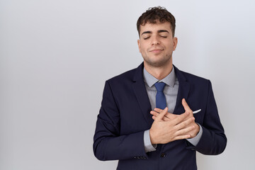 Young hispanic business man wearing suit and tie smiling with hands on chest with closed eyes and grateful gesture on face. health concept.