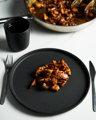 Chicken Tocino. Chicken in gooey sweet glaze. Caramelised chicken thighs in sweet sauce on black plate.