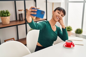 Fototapeta na wymiar Young beautiful hispanic woman make selfie by smartphone sitting on table at home