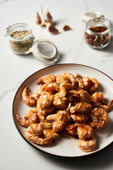 Crispy Pan fried tiger shrimps or prawns with garlic. Chinese or Asian cuisine dish. Shrimps lay on white plate on white marble background. T
