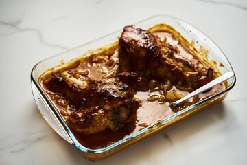 Smothered or stewed Turkey wings in a rectangular baking dish. Roasted to a crisp, the wings lie drowned in a thick gravy with vegetables. Food photo.