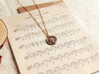 Composition with a necklace and a old music sheet on beige background. Vintage fashion concept and jewelry minimalist style. Autumn, fall mockup.