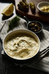 Classic Tartar Sauce with it ingredients on dark stone or marble background. Mayonnaise with dill and pickled cucumbers with lemon. 