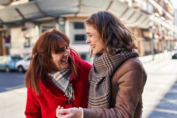 Two women mother and daughter standing together speaking at street