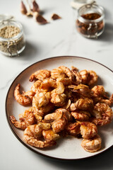 Crispy Pan fried tiger shrimps or prawns with garlic. Chinese or Asian cuisine dish. Shrimps lay on white plate on white marble background. T