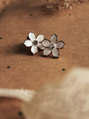 A pair of small flower earrings, on a polka dot background. Vintage fashion concept and minimalist style. Composition with female accessories. 