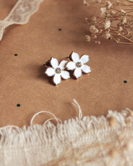 A pair of small flower earrings and dry flowers on a polka dot background. Vintage fashion concept...