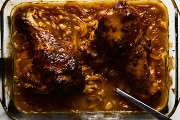 Smothered or stewed Turkey wings in a rectangular baking dish. Roasted to a crisp, the wings lie drowned in a thick gravy with vegetables. Food photo.