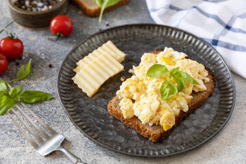 Scrambled eggs on whole grain bread on a stone table. Homemade breakfast or brunch meal - scrambled eggs.