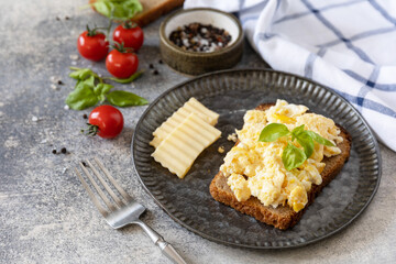Scrambled eggs on whole grain bread on a stone table. Homemade breakfast or brunch meal - scrambled eggs. Copy space.