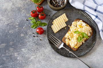 Homemade breakfast or brunch meal - scrambled eggs. Scrambled eggs on whole grain bread on a stone table. View from above.
