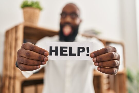 African american man holding help reminder sticking tongue out happy with funny expression.