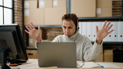 Middle age hispanic woman ecommerce business call center agent having video call at storehouse...