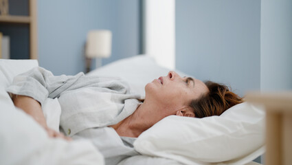Fototapeta na wymiar Middle age hispanic woman worried lying on bed at bedroom
