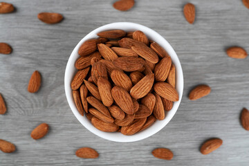 A bowl of almonds on the table. Scattering of almonds. Healthy snack with nuts.