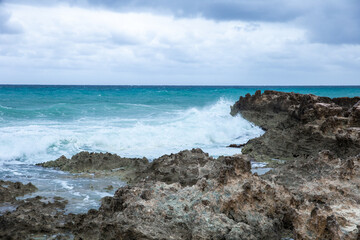 Fototapeta na wymiar Tropical storm in the Atlantic Ocean. Beautiful rocky shore with rolling waves. Hurricane in Caribbean Sea, Gulf of Mexico, Cancun.