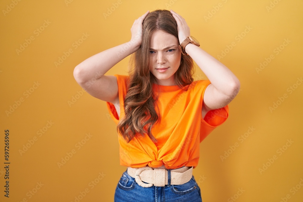 Poster caucasian woman standing over yellow background suffering from headache desperate and stressed becau