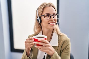 Young blonde woman call center agent drinking coffee at office