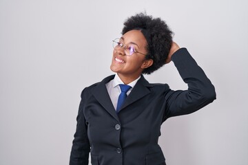 Beautiful african woman with curly hair wearing business jacket and glasses smiling confident touching hair with hand up gesture, posing attractive and fashionable