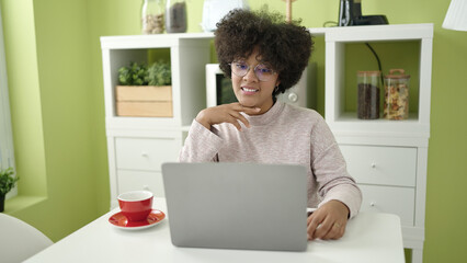 Young african american woman using laptop sitting on table at home