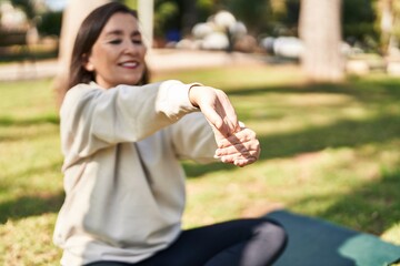 Middle age woman smiling confident stretching at park