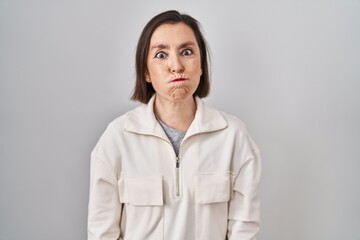Middle age hispanic woman standing over isolated background puffing cheeks with funny face. mouth inflated with air, crazy expression.