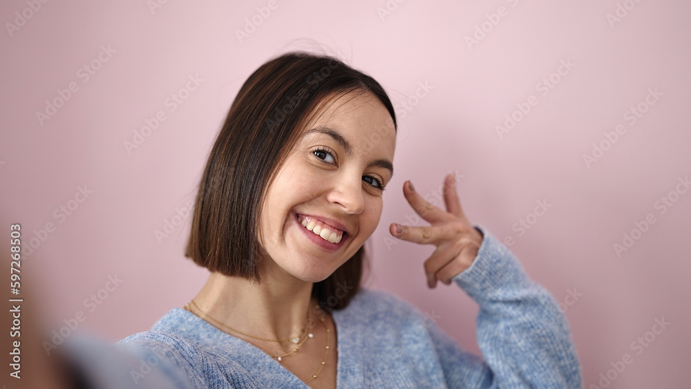 Canvas Prints Young beautiful hispanic woman smiling confident make selfie by camera over isolated pink background