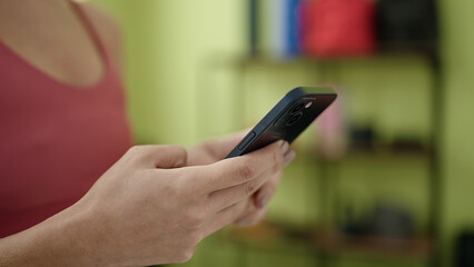 Young beautiful hispanic woman using smartphone at sport center