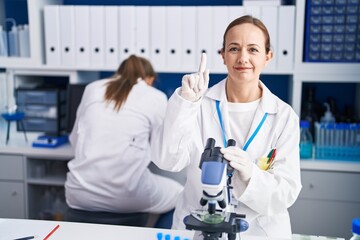 Blonde woman working on cruelty free laboratory surprised with an idea or question pointing finger with happy face, number one