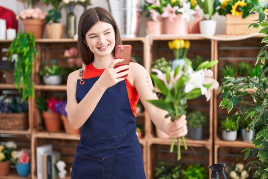 Young caucasian woman florist make photo by smartphone to flowers at florist