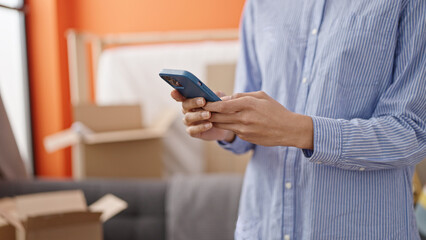 Young beautiful hispanic woman using smartphone at new home