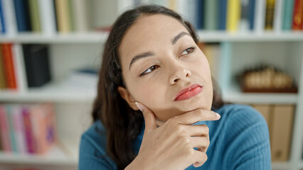 Young beautiful hispanic woman thinking at university classroom