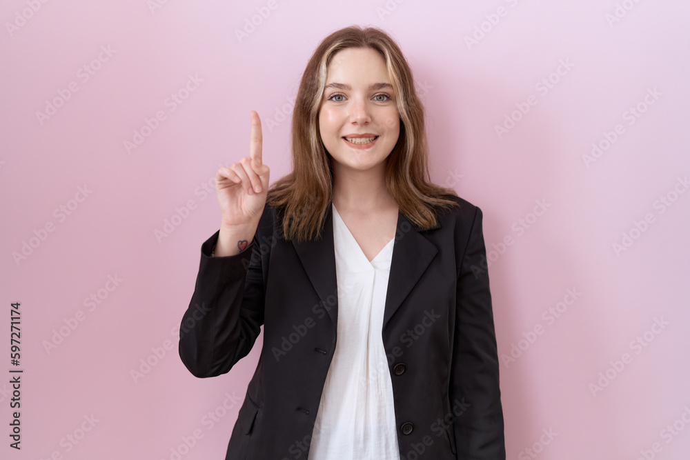 Sticker Young caucasian business woman wearing black jacket showing and pointing up with finger number one while smiling confident and happy.