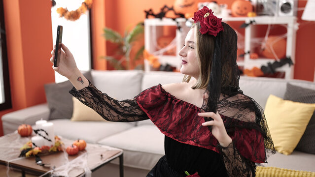 Young blonde woman wearing katrina costume making selfie by smartphone at home