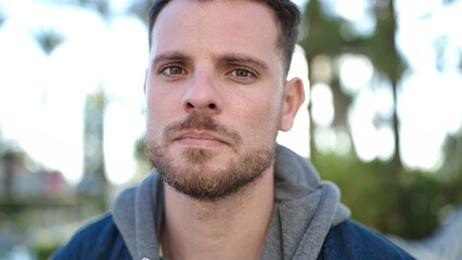 Obraz premium Young caucasian man standing with serious expression at park
