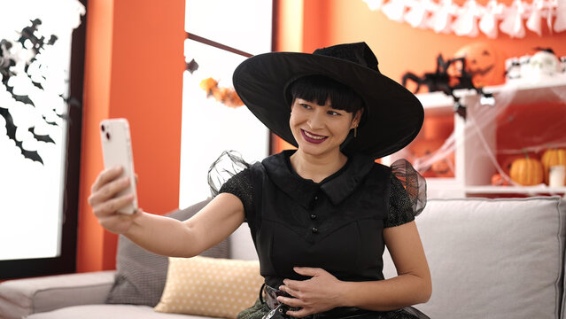 Young chinese woman wearing witch costume make selfie by smartphone at home