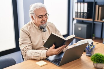 Middle age grey-haired man business worker using laptop reading book at office