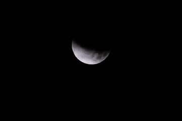a full moon in the southern sky is covered almost completely by the Earths shadow in a partial...