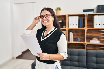 Young beautiful hispanic woman business worker reading document at office