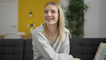 Fototapeta premium Young blonde woman smiling confident sitting on the sofa at home